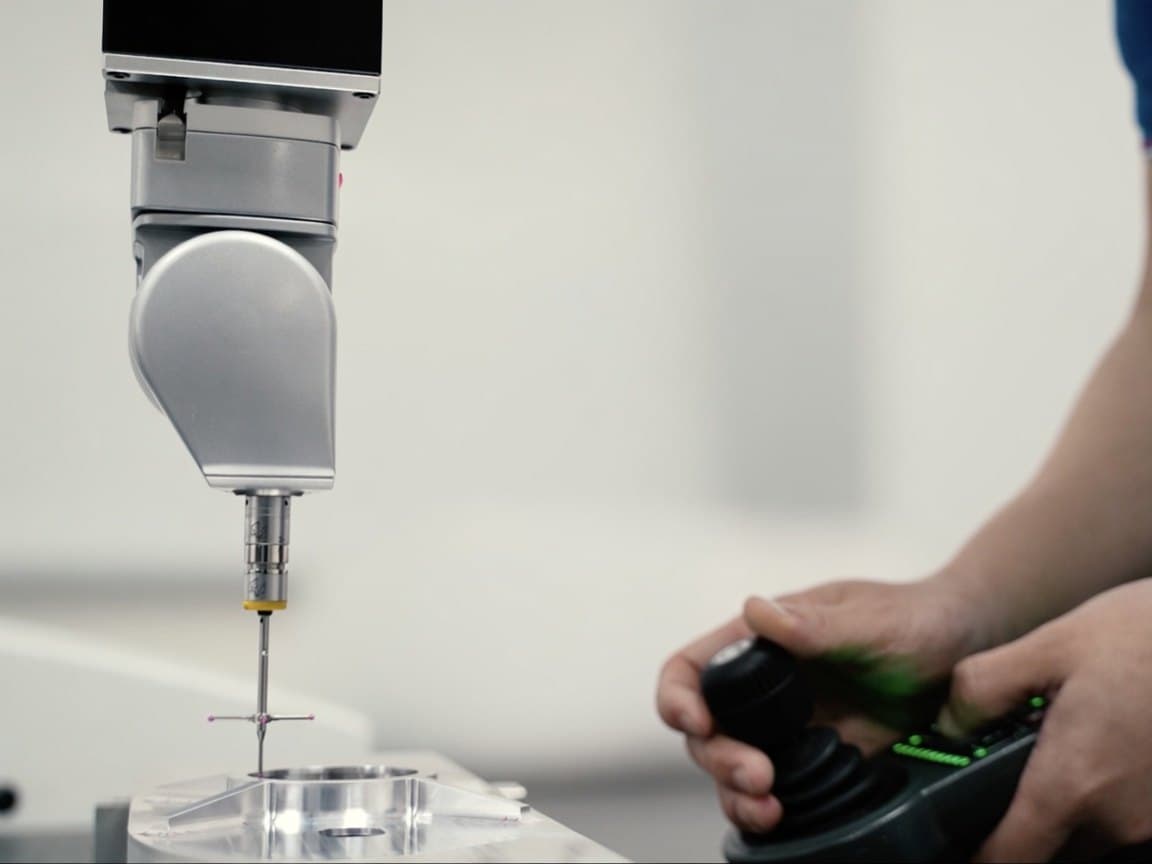 CMM probe inspecting a machined part, operator on the joystick